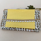 Yellow clutch bag with decorative trim on a light background