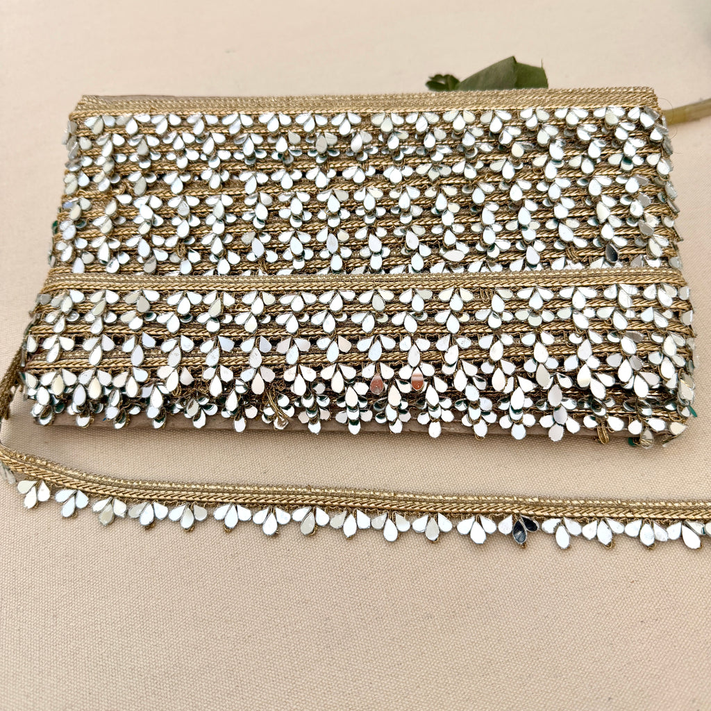 Beaded clutch bag with gold and white accents on a beige background