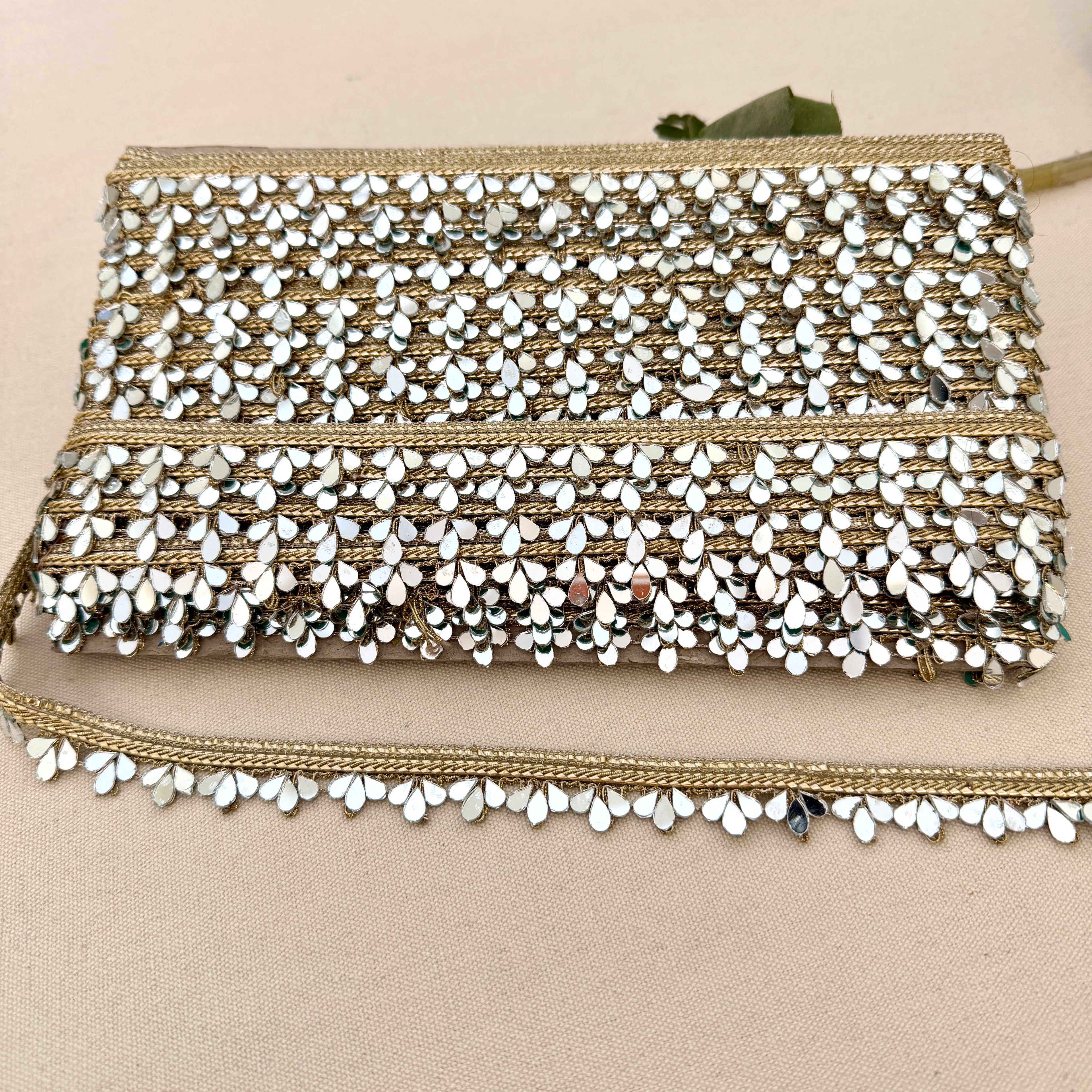 Beaded clutch bag with gold and white accents on a beige background