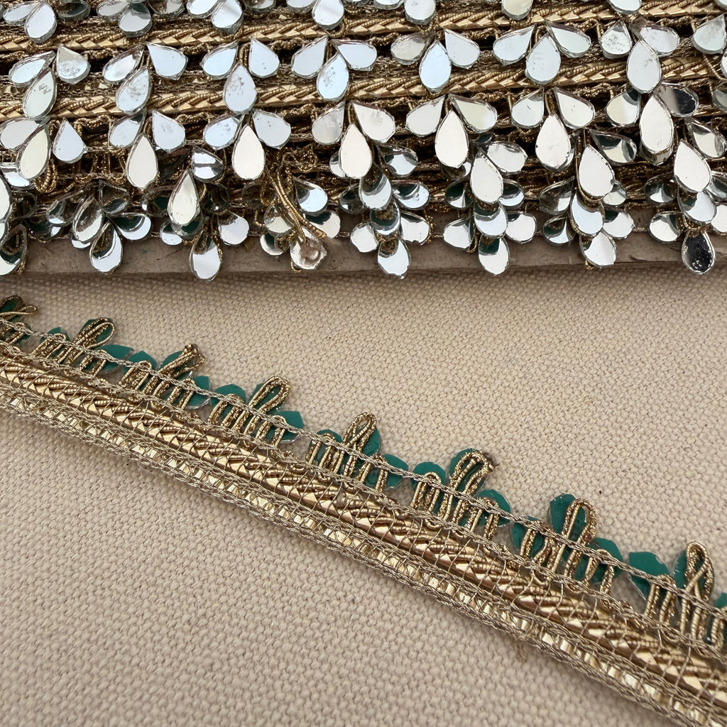 Close-up of decorative fabric trim with gold and silver details on a beige background