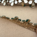 Close-up of decorative headband with gold and green embellishments on a beige fabric background