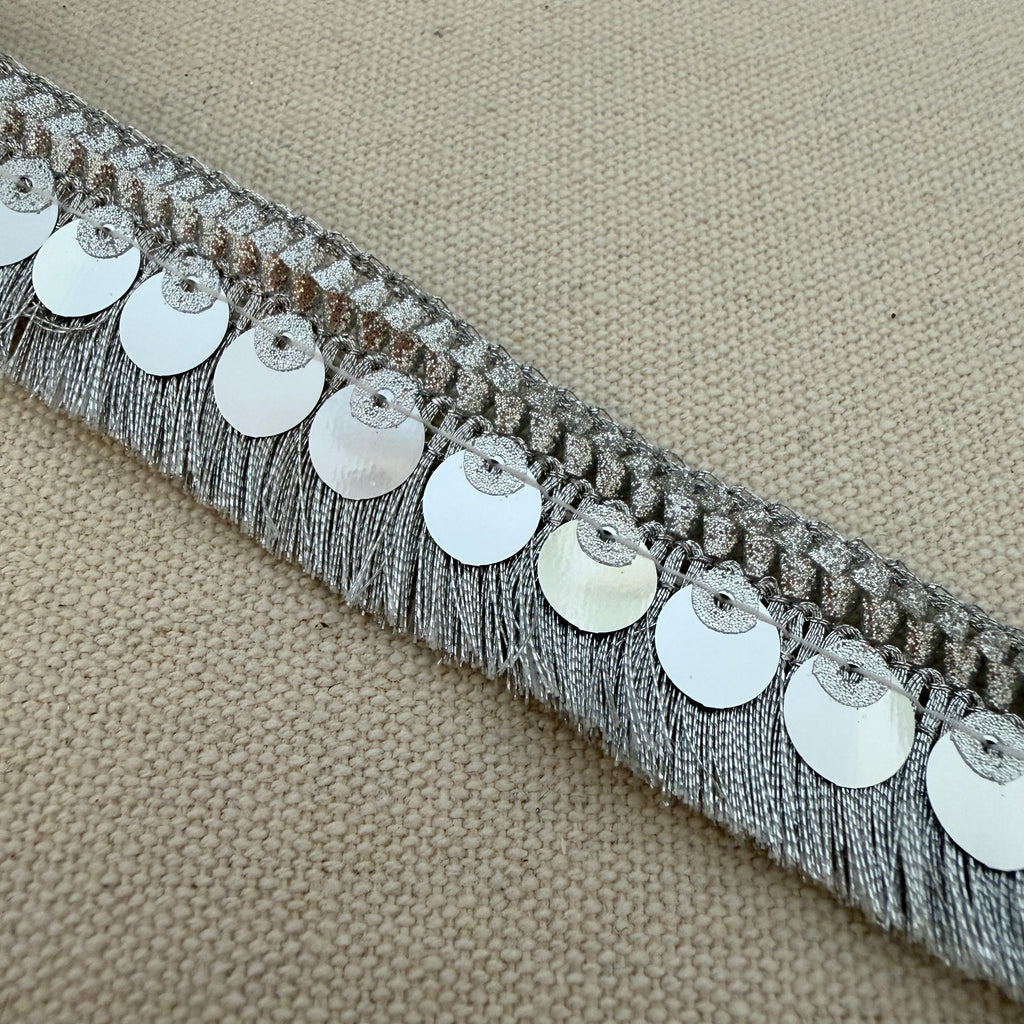 Decorative trim with silver sequins on a beige fabric background