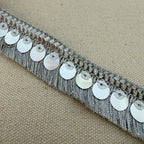 Decorative trim with silver sequins on a beige fabric background