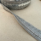 Close-up of a textured gray ribbon on a beige fabric background