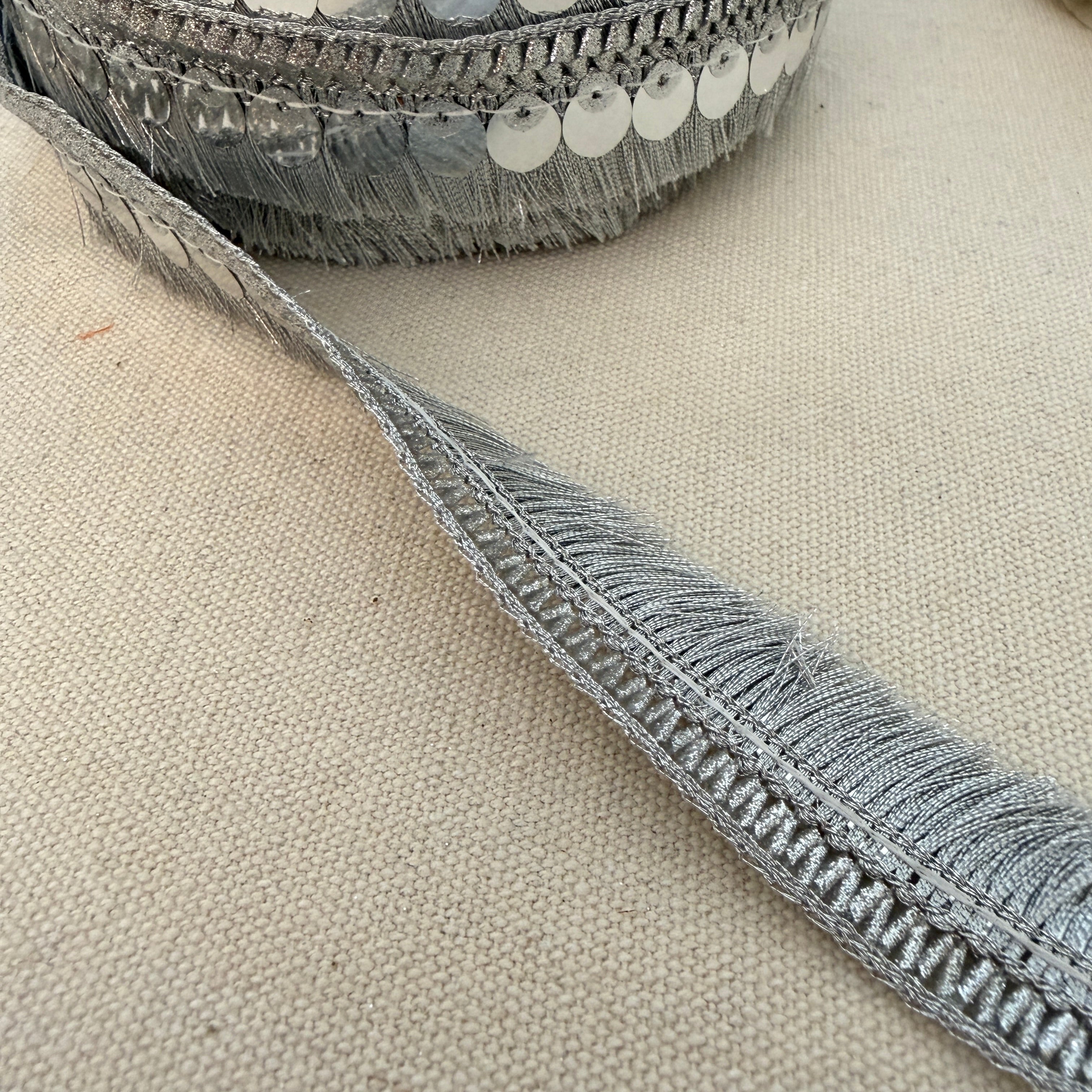 Close-up of a textured gray ribbon on a beige fabric background