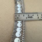 Sequined trim with a ruler for scale on a beige background