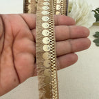 Gold lace trim held between fingers with a white flower in the background