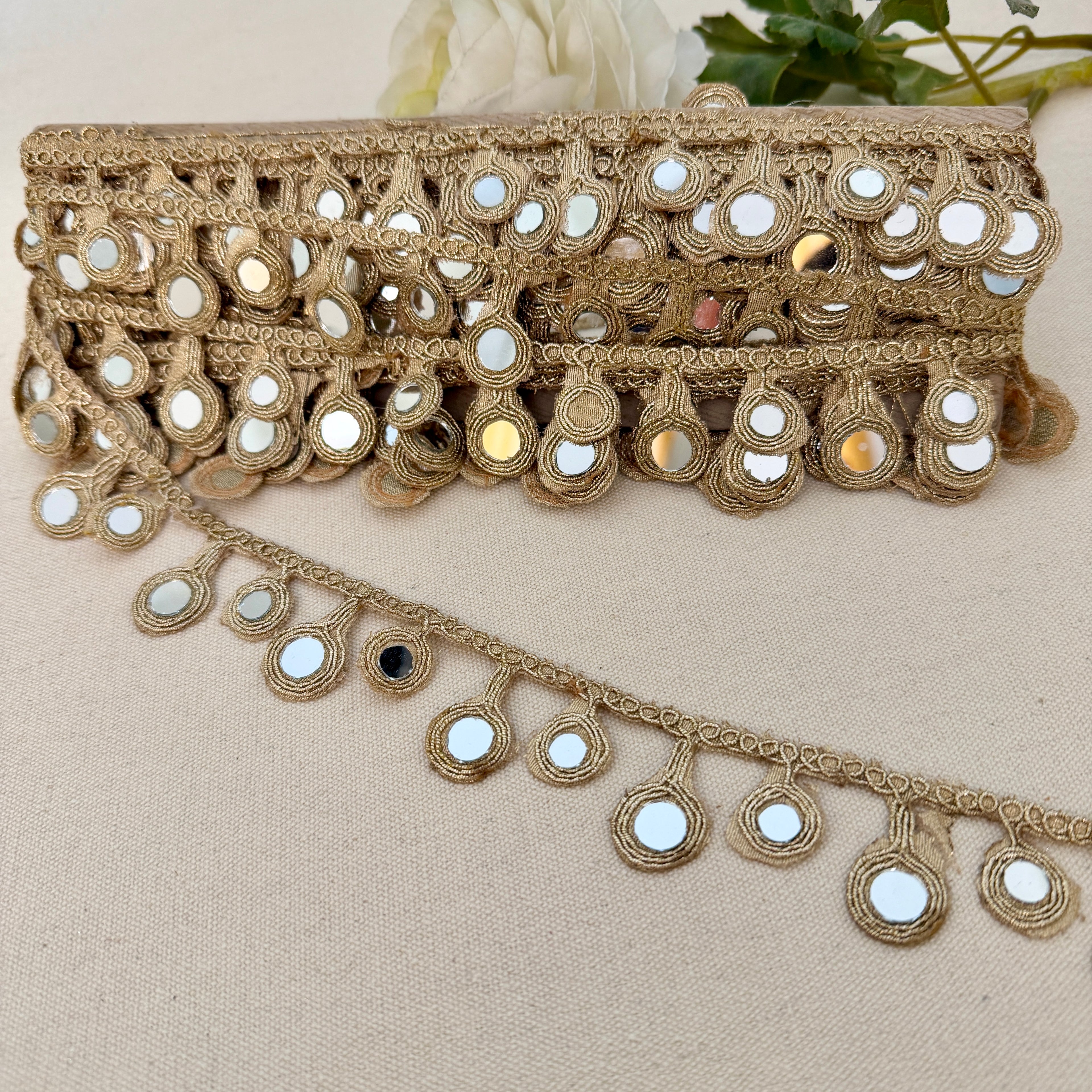 Decorative lace trim with mirrors on a beige fabric background