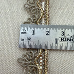 Three gold chains draped over a ruler on a textured beige background