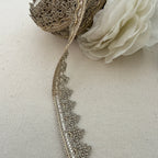 Decorative lace trim with a white flower on a beige fabric background