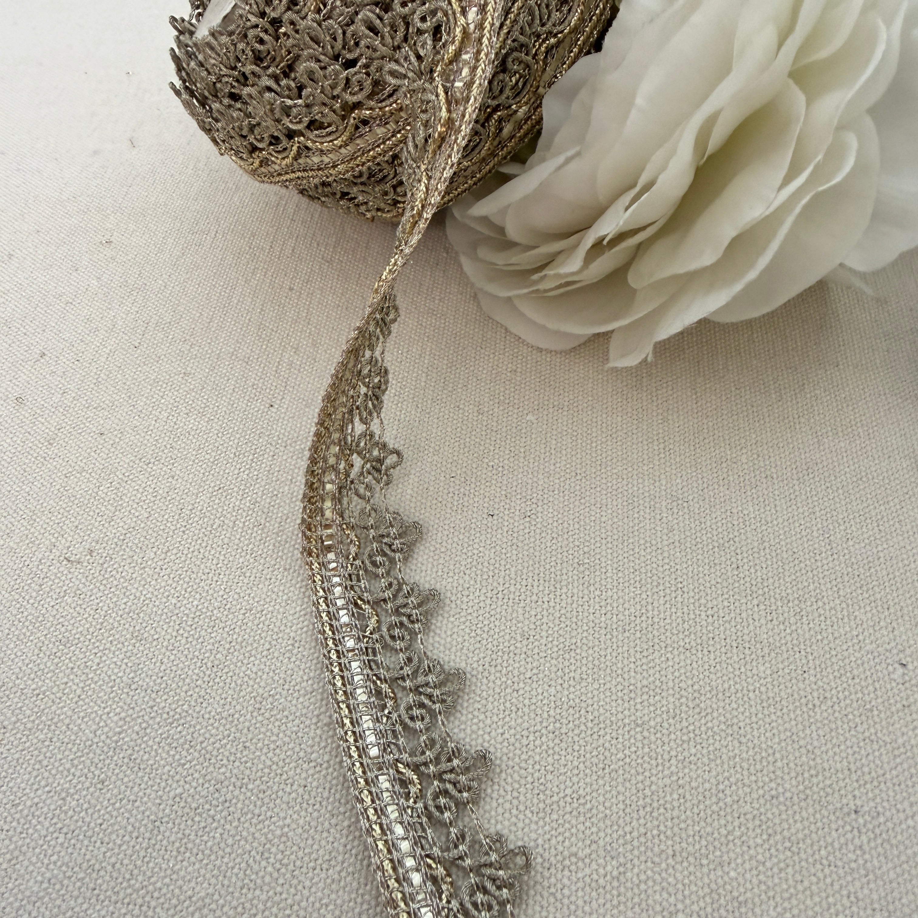 Decorative lace trim with a white flower on a beige fabric background
