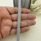 Close-up of decorative lace trim held between fingers with a floral background