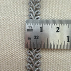 Silver braided cord with a ruler for measurement on a beige fabric background