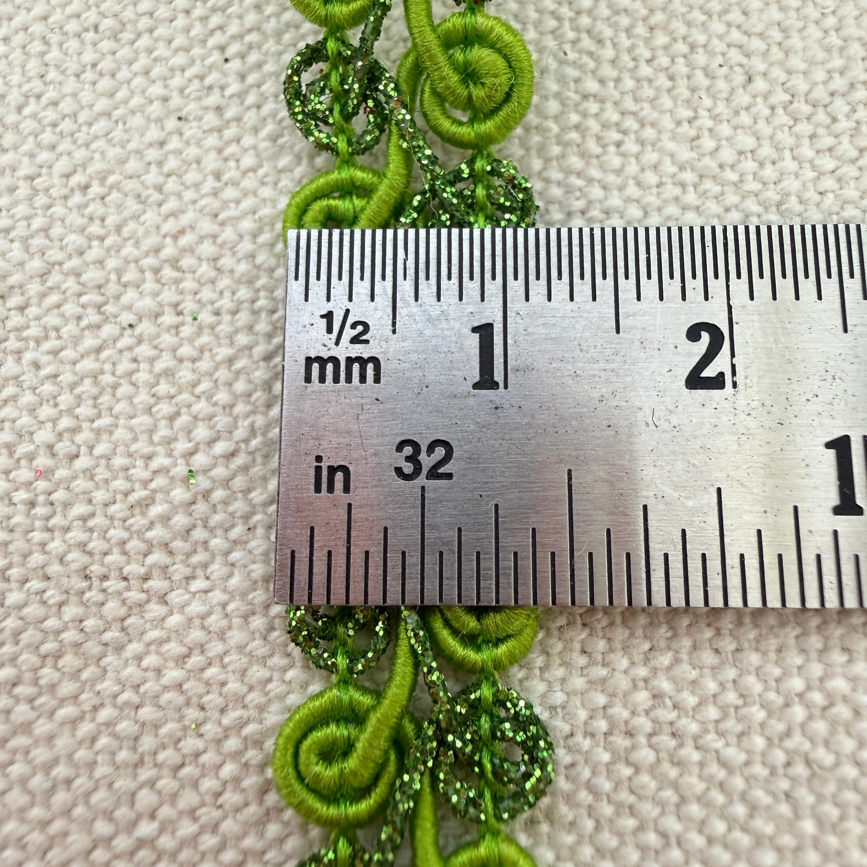 Green decorative trim with a ruler for scale on a textured beige background
