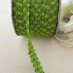 Green decorative ribbon on a spool with a white flower on a beige background
