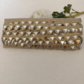 Gold clutch with mirror-like embellishments on a beige background