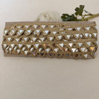 Gold clutch with mirror-like embellishments on a beige background