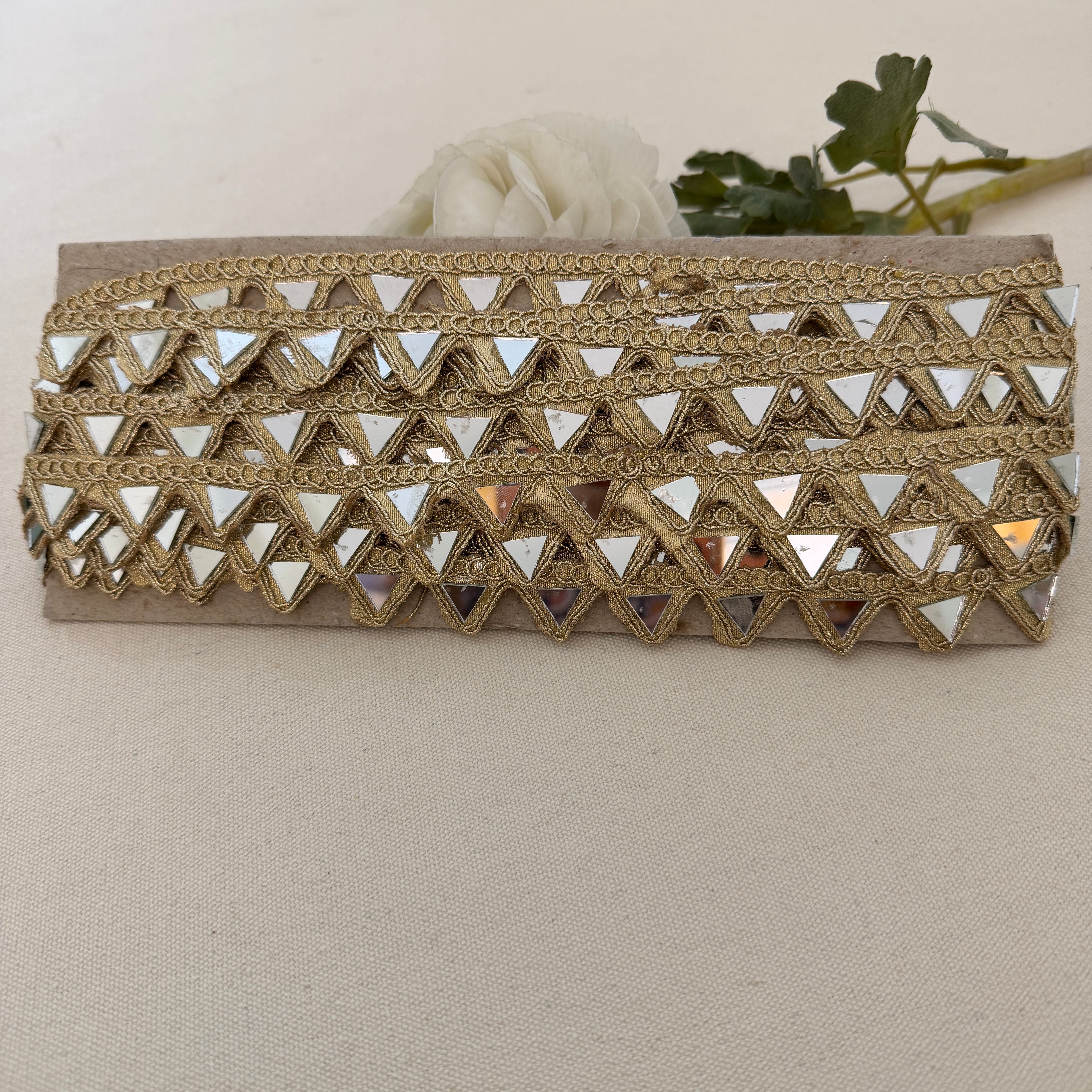 Gold clutch with mirror-like embellishments on a beige background