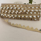 Gold embroidered clutch bag with intricate patterns on a beige fabric background