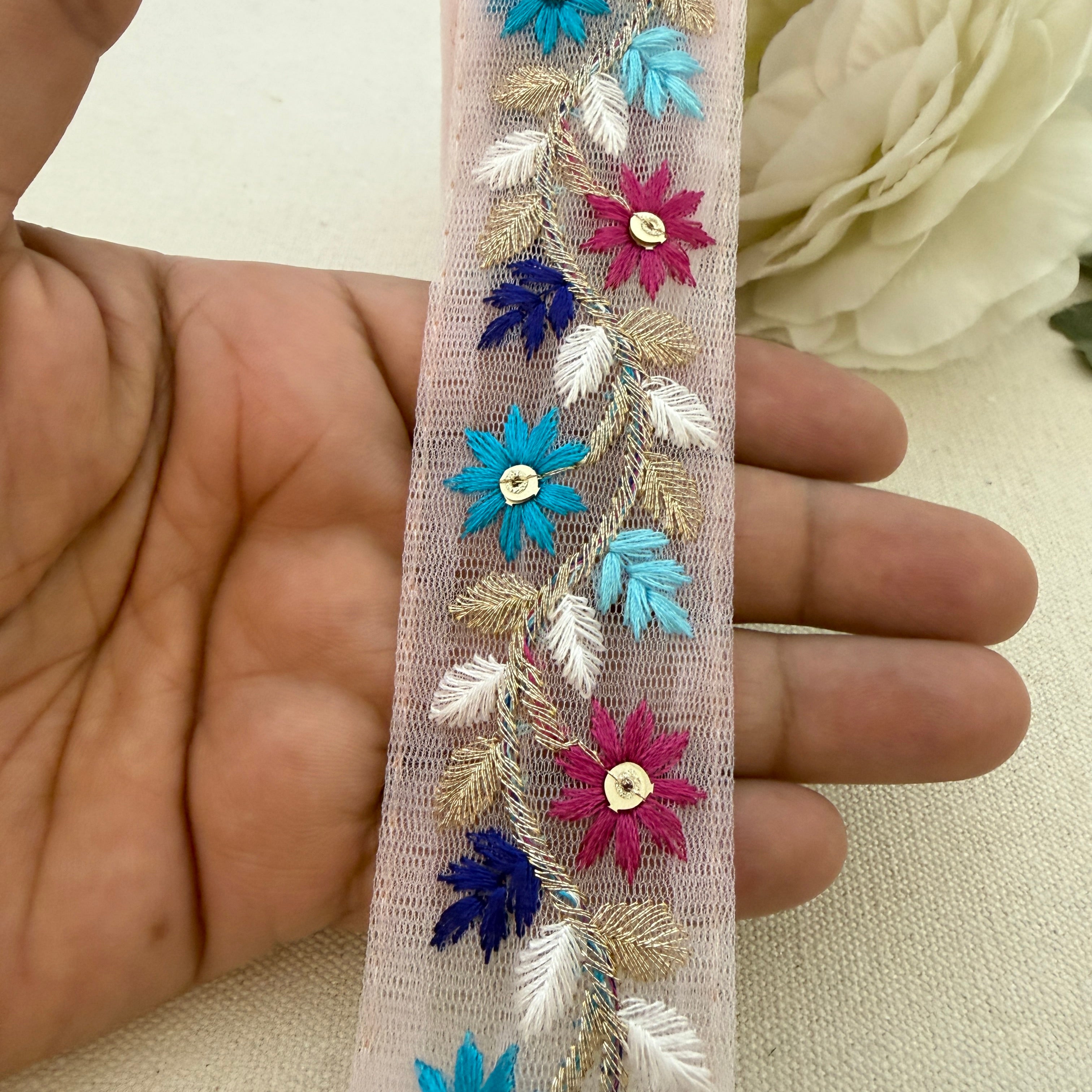 Decorative ribbon with floral and leaf patterns held between fingers