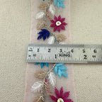 Decorative fabric strip with flowers and leaves measured against a ruler on a beige background