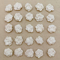 Pattern of white crocheted flowers on a beige fabric background
