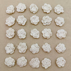 Pattern of white crocheted flowers on a beige fabric background