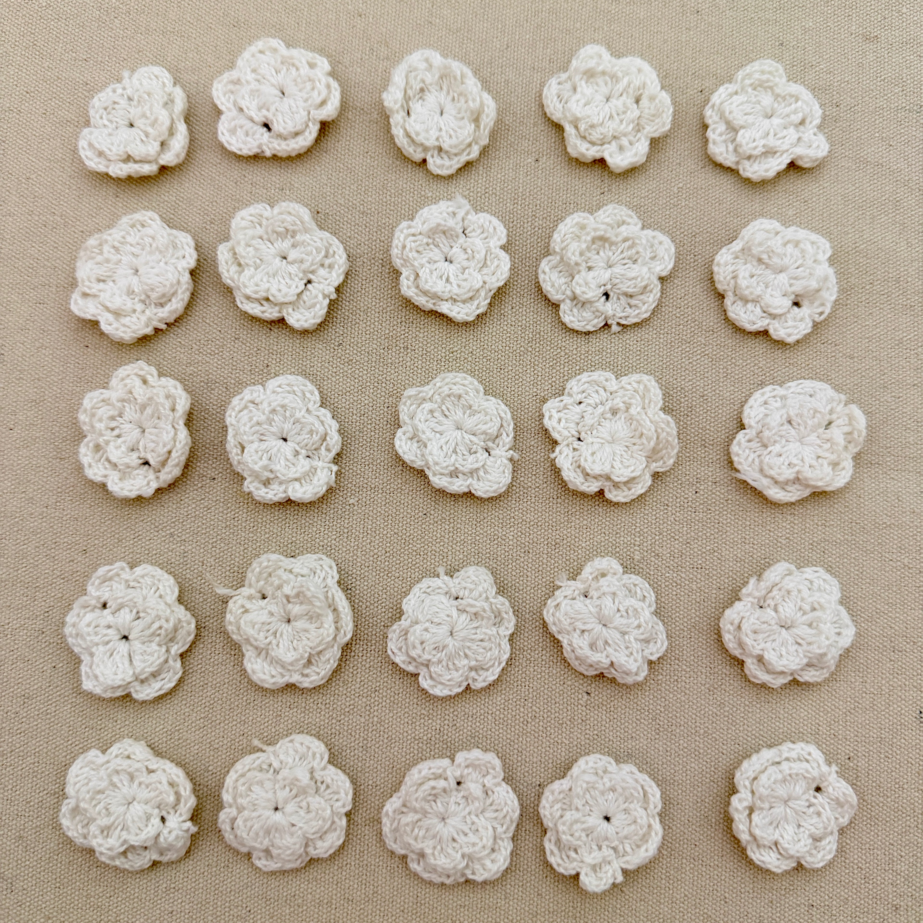 Pattern of white crocheted flowers on a beige fabric background