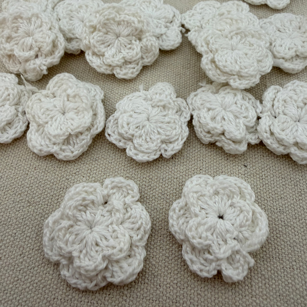 White crocheted flowers on a beige fabric background