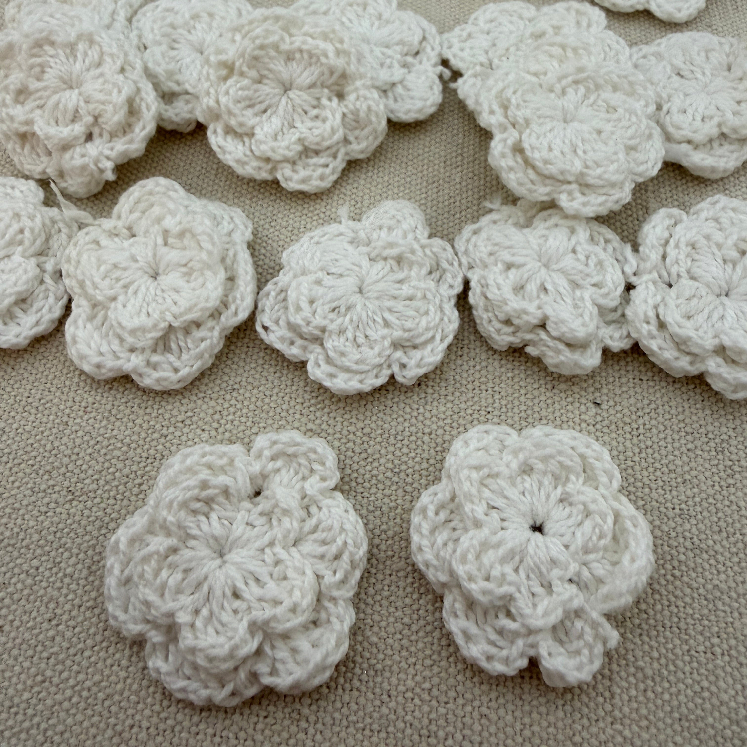 White crocheted flowers on a beige fabric background