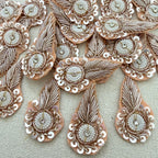 Decorative fabric patch with intricate gold and silver embroidery on a beige background
