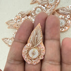 Decorative rose gold and white embroidered patch on a hand with a beige background