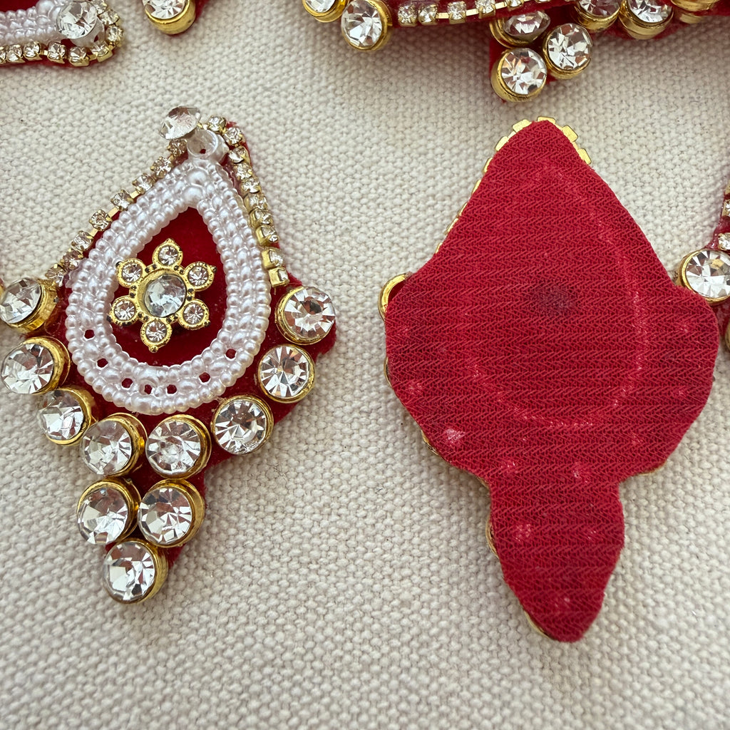 Decorative red and gold earrings with gemstones on a textured beige background
