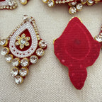 Decorative red and gold earrings with gemstones on a textured beige background