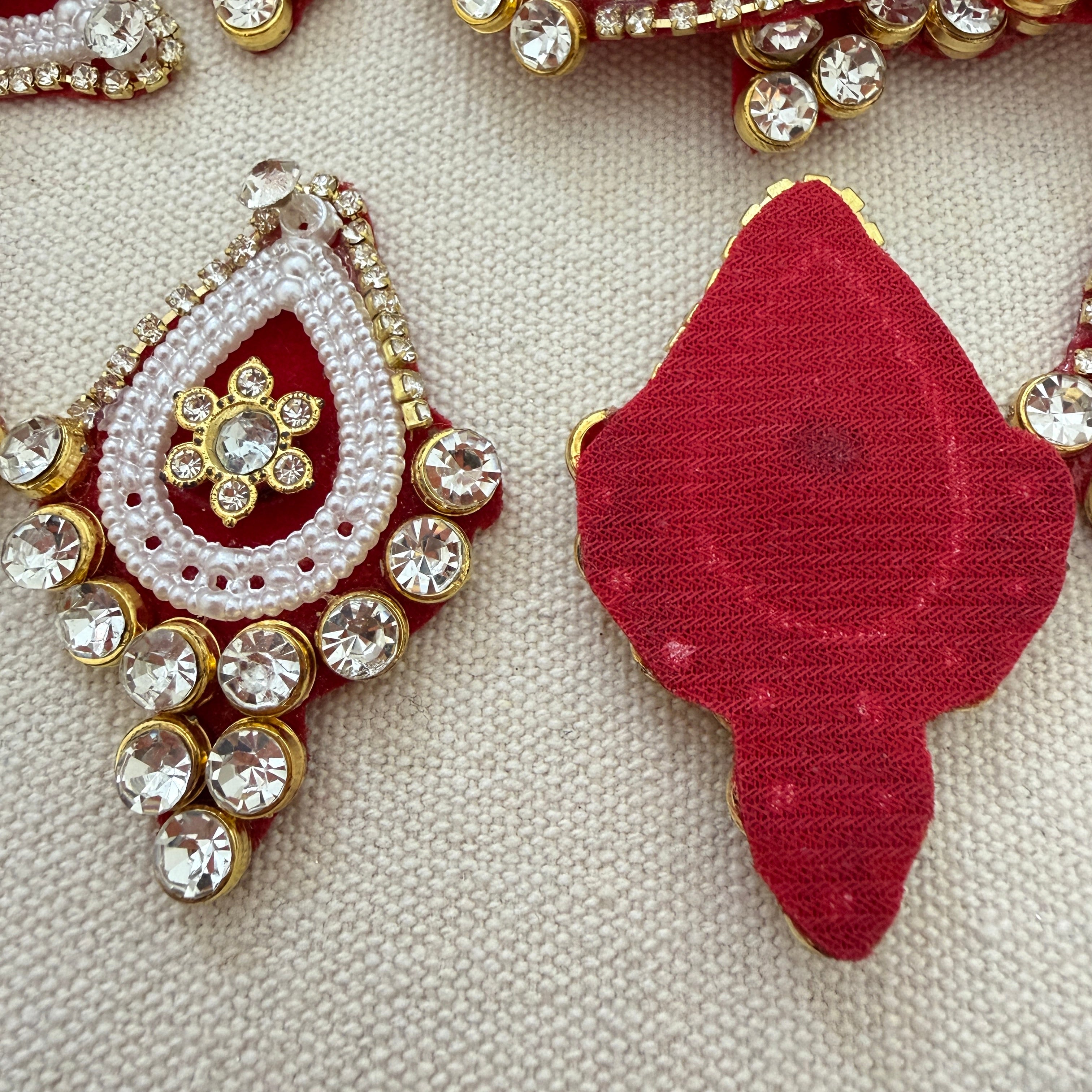 Decorative red and gold earrings with gemstones on a textured beige background