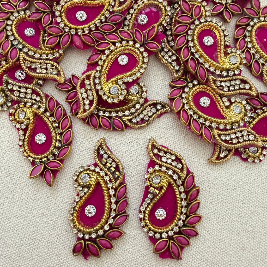 Decorative pink and gold earrings with gemstones on a light background