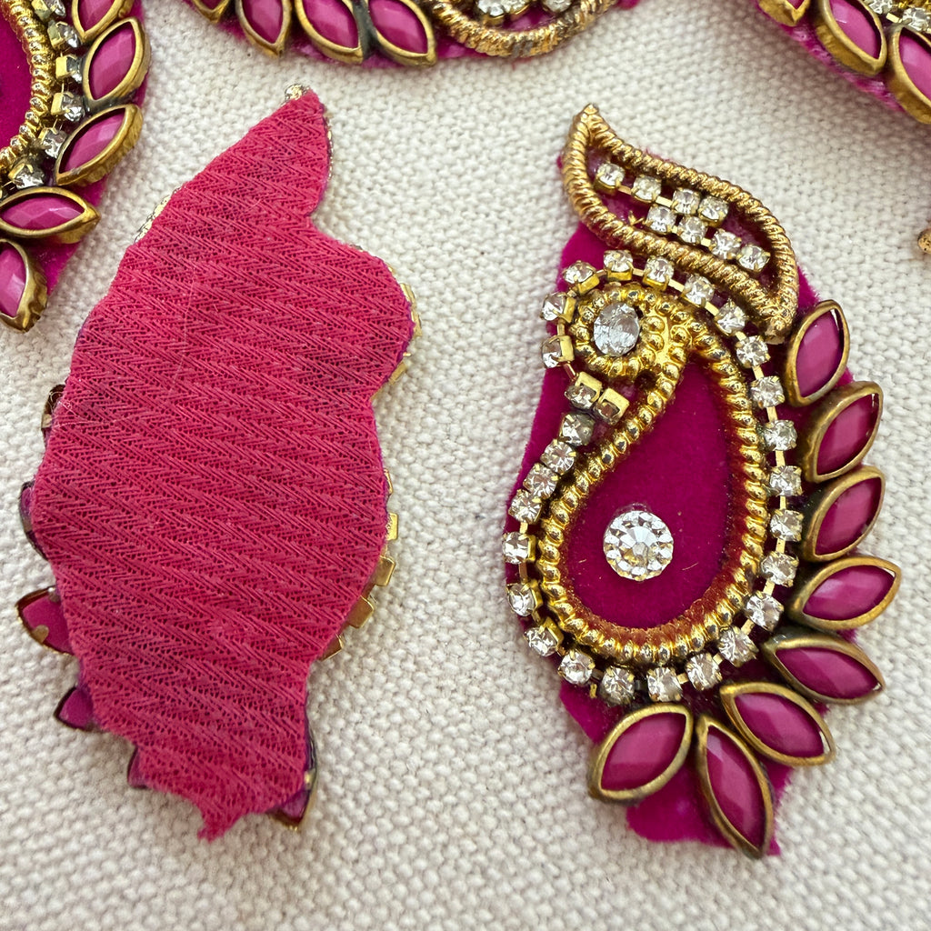 Decorative pink and gold embellishment on a textured white background