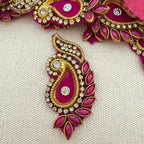 Decorative pink and gold jewelry piece with gemstones on a light gray background
