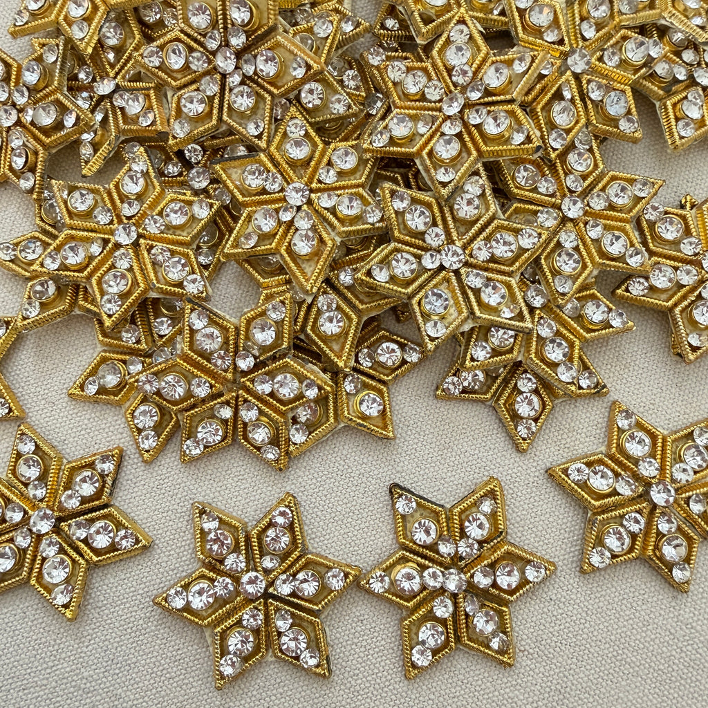 Gold and crystal star-shaped embellishments on a beige fabric background