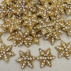 Gold and crystal star-shaped embellishments on a beige fabric background