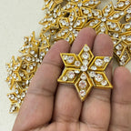 Gold and crystal decorative patch held between fingers with more patches in the background.