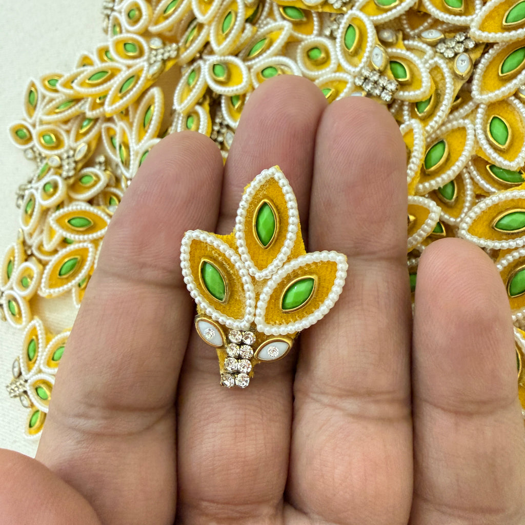 Gold and green decorative brooch on a hand with a patterned background