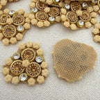 Decorative brooches with gold and crystal details on a textured beige background