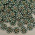 Close-up of decorative embellishments with green, gold, and clear stones on a gray background