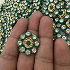 Close-up of a hand holding a decorative gemstone with a background of similar gems.