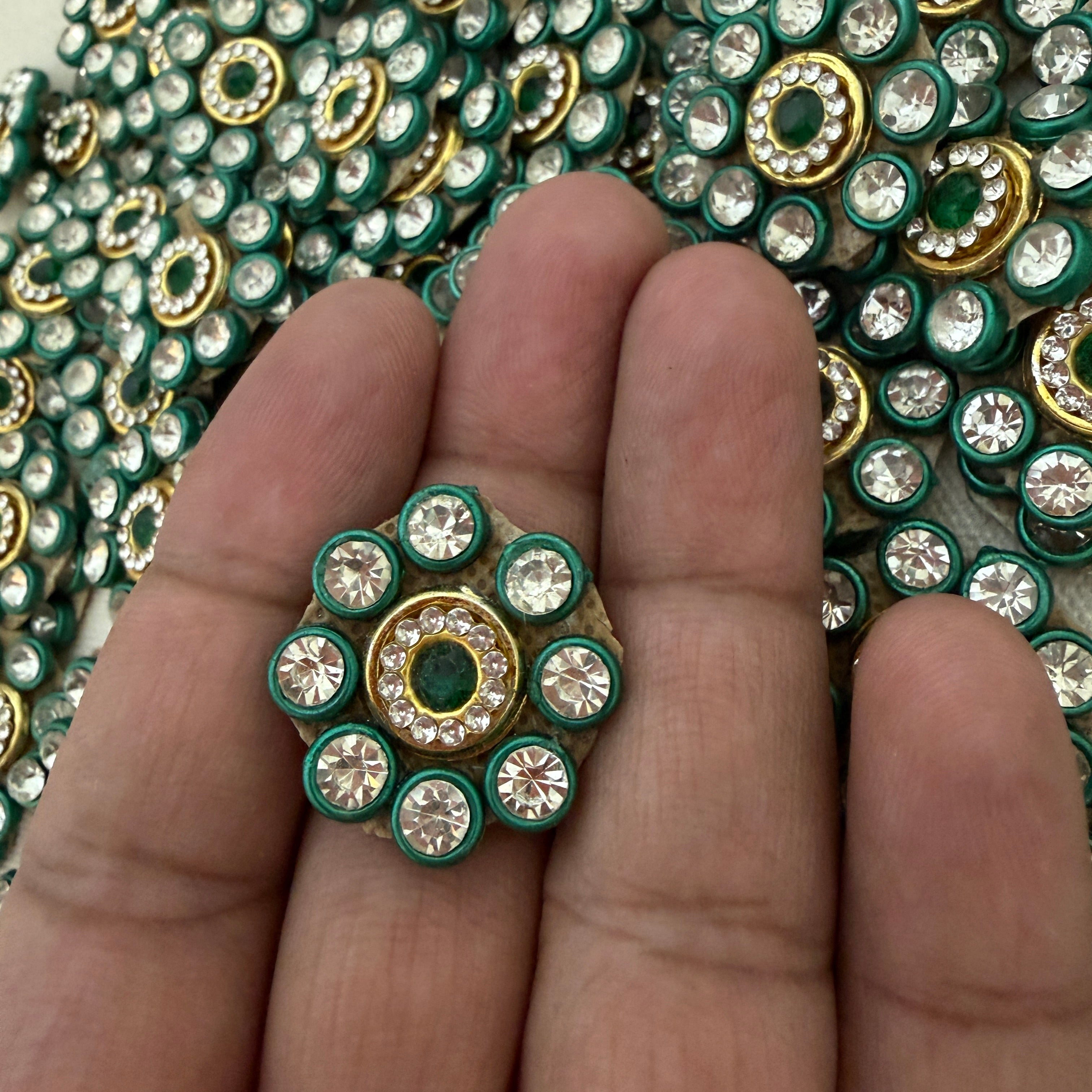 Close-up of a hand holding a decorative gemstone with a background of similar gems.