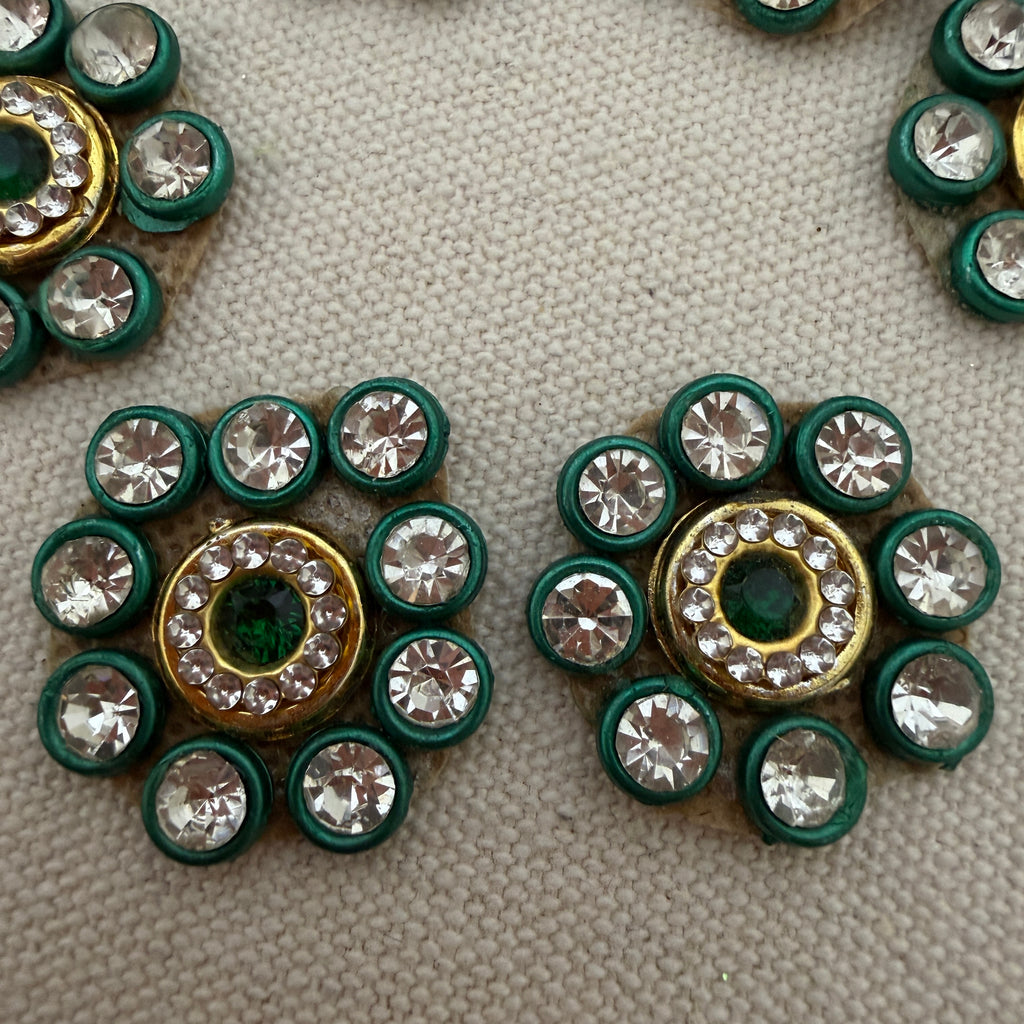 Decorative buttons with green and gold circular designs on a textured surface