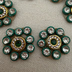 Decorative buttons with green and gold circular designs on a textured surface