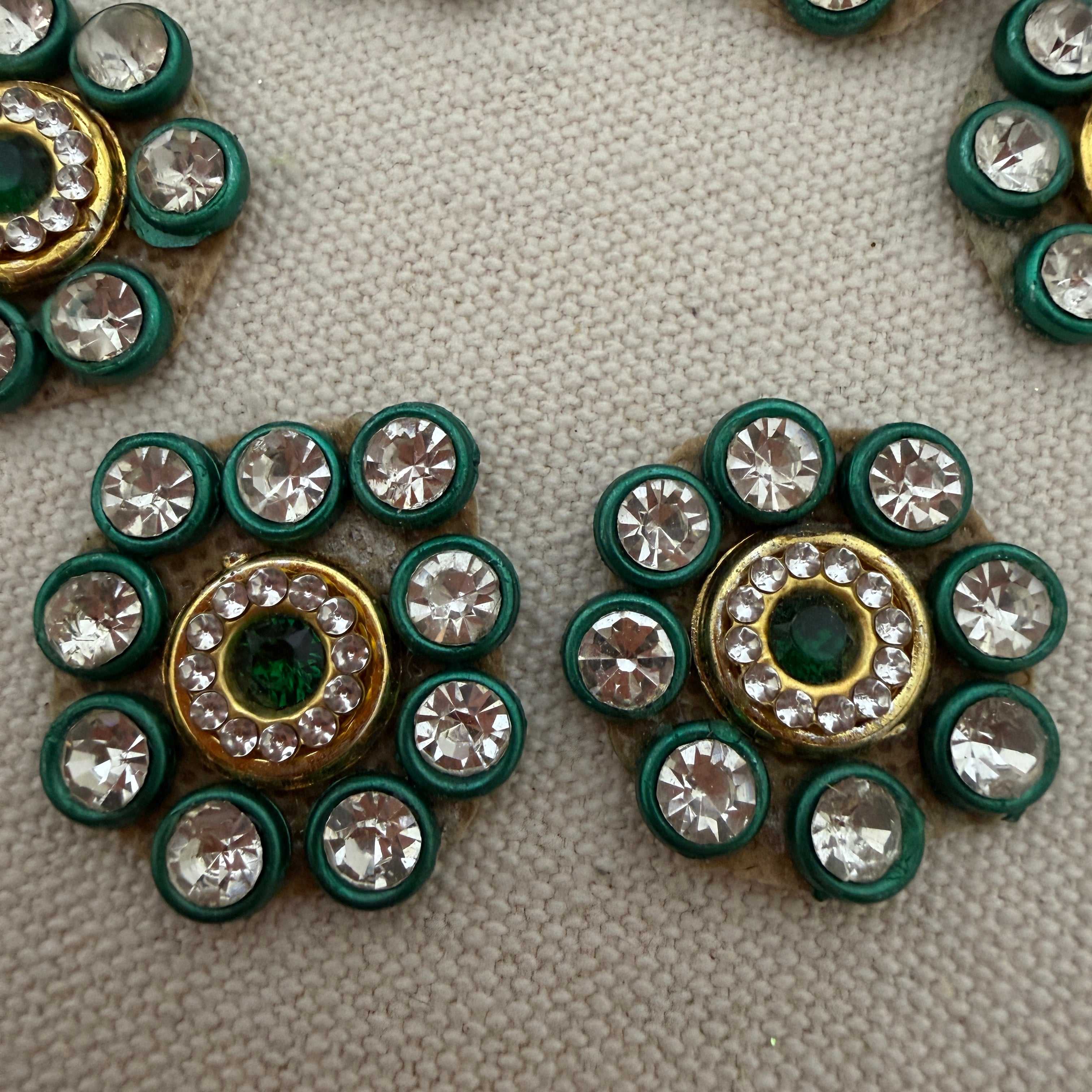 Decorative buttons with green and gold circular designs on a textured surface