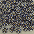 Close-up of decorative embellishments with blue centers and gold and silver accents on a neutral background.